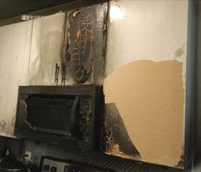 Fire damaged cabinet and microwave.