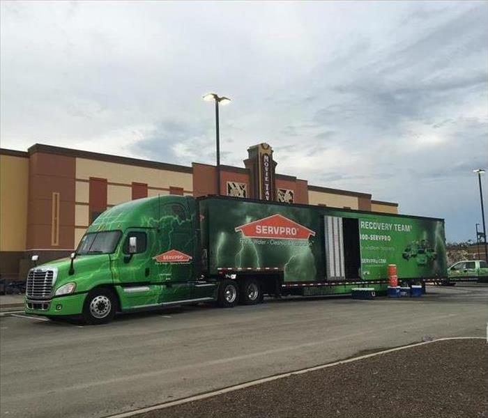 Green SERVPRO semi truck parked in front of a commercial building