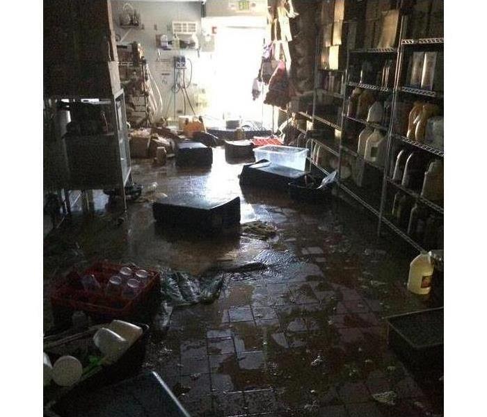 storage room of a restaurant with flooded waters on the floor, bins, boxes canned food damaged by water