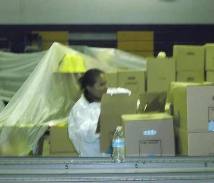 Woman wearing protective gear while packing out items on boxes to restore